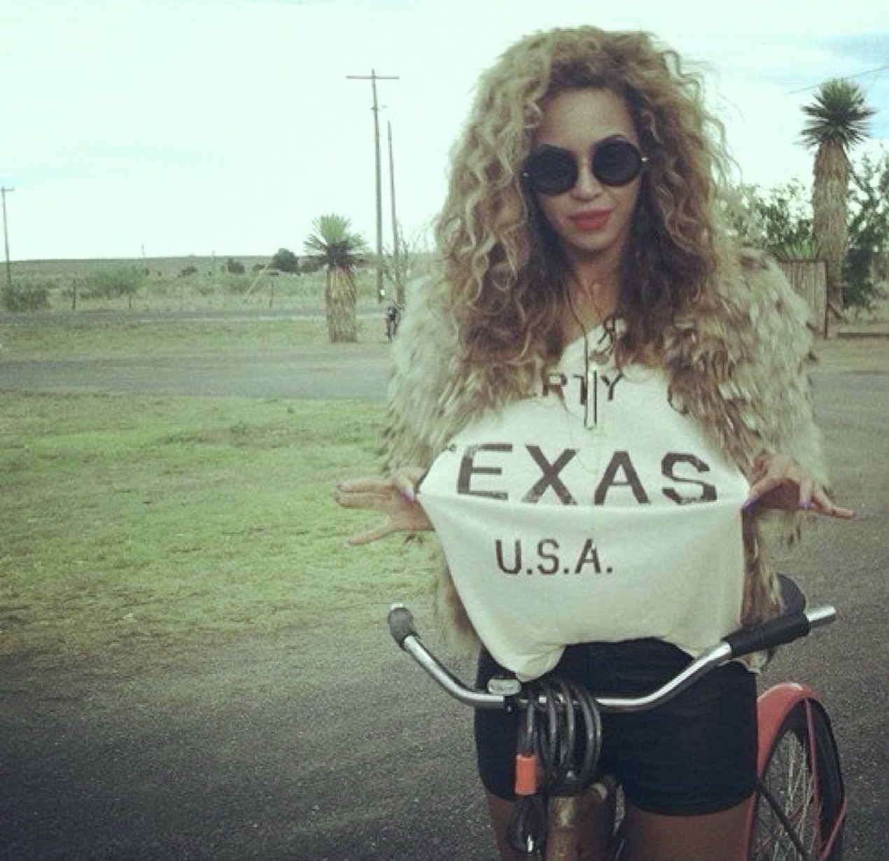 Beyoncé on bike with sunglasses and Texas USA shirt